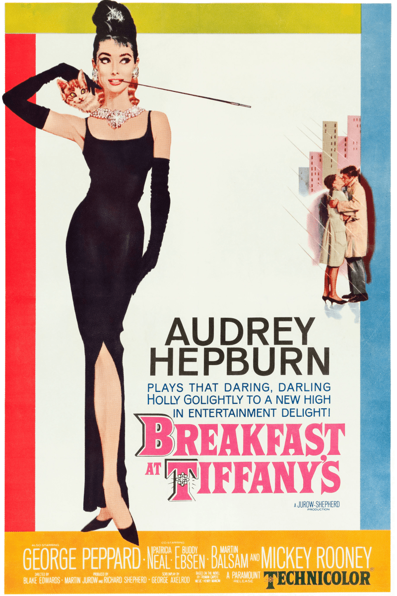 A vintage Breakfast at Tiffany’s movie poster features an illustrated full‑length image of Audrey Hepburn in a long black dress with black gloves, a pearl necklace, and a cigarette holder, with a cat on her shoulder. A smaller background illustration shows a couple embracing near a cityscape, and the poster includes colorful borders along with cast and production credits.